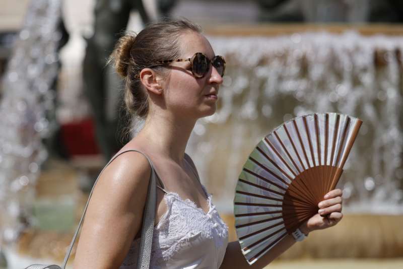 Una viandante se abanica para combatir el calor mientras pasea por Valencia. EFE Ana Escobar
