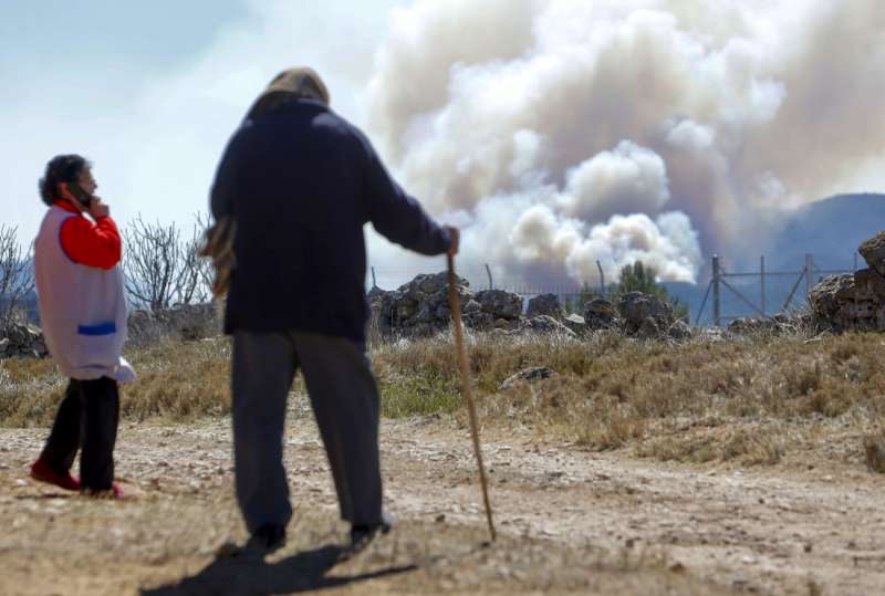 Dos vecinos observan el humo generado por el incendio de Villanuena de Viver (Castellón), que desde el pasado jueves ha calcinado cerca de 4.000 hectáreas. EFE/ Domenech Castelló
