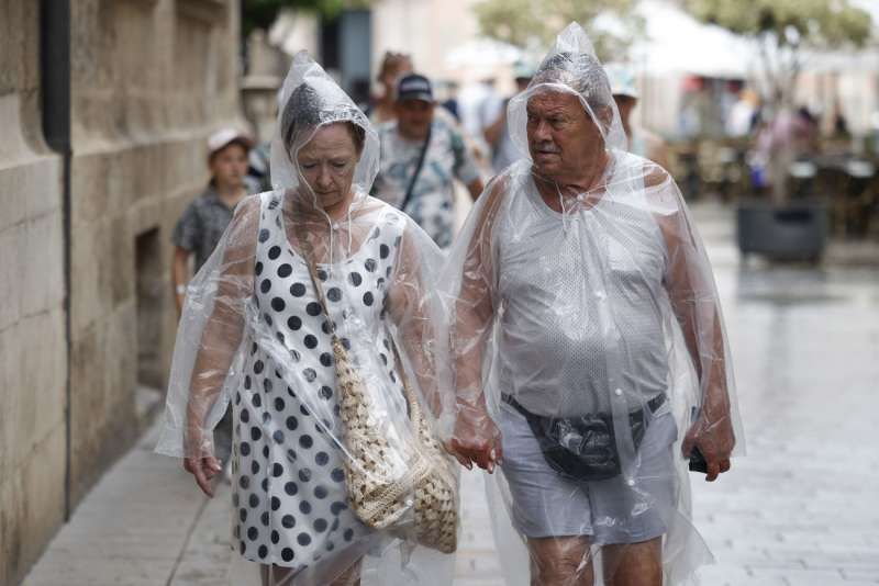 Dos personas se protegen de la lluvia. Archivo EFE BIEL ALIO
