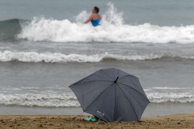 Una persona se baña bajo la lluvia en las aguas de la playa de El Postiguet de Alicante. /EFE