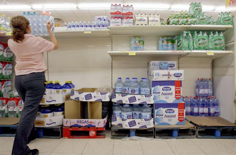 Una trabajadora repone botellas de agua en los estantes de un supermercado. /EFE