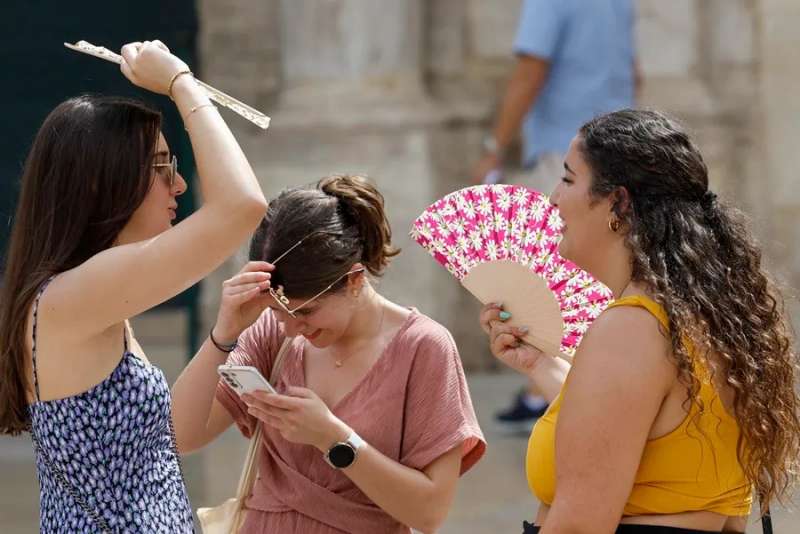 Tres personas se protegen del calor con abanicos mientras pasea por el centro de Valencia. EFEKai F�rsterling
