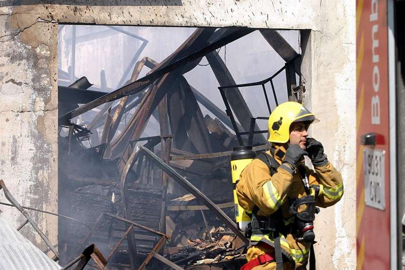 Un bombero sale de una fábrica totalmente destruida por un incendio. EFE/Morell/Archivo
