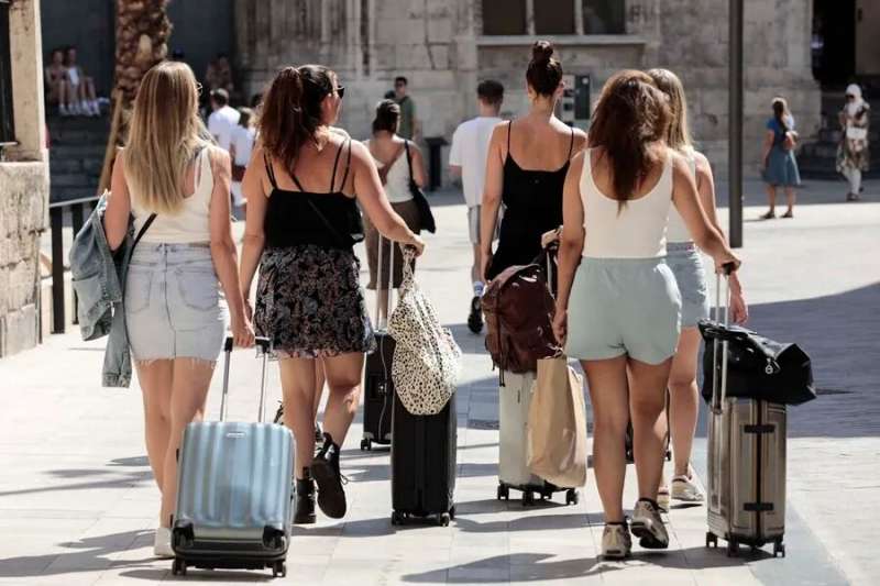 Un grupo de turistas caminan con sus maletas por el centro de Valencia. EFE/Ana Escobar


