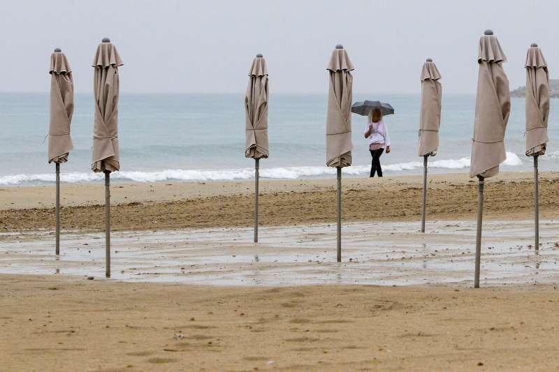 Una persona pasea bajo la lluvia por la playa de El Postiguet de Alicante. ARchivoEFEMorell