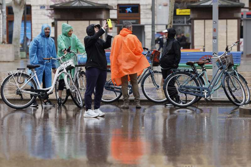 Varias personas se protegen de la lluvia con chubasqueros por las calles de Valencia, este domingo. EFE Ana EscobarArchivo
