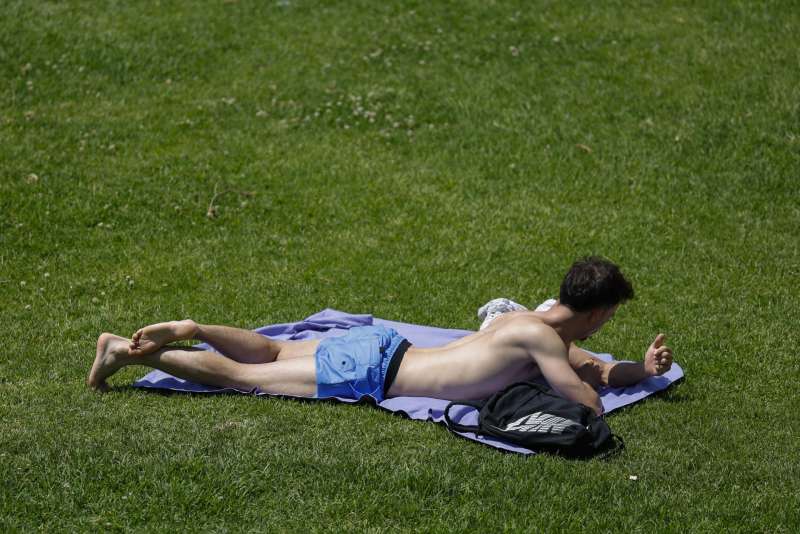 Una persona toma el sol en los jardines del antiguo cauce del Turia. EFEAna EscobarArchivo
