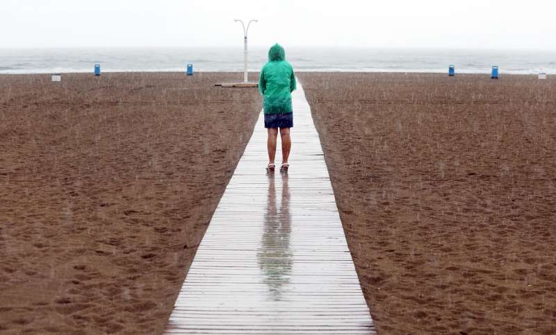 Una mujer contempla una playa bajo la lluvia. EFEKai FrsterlingArchivo
