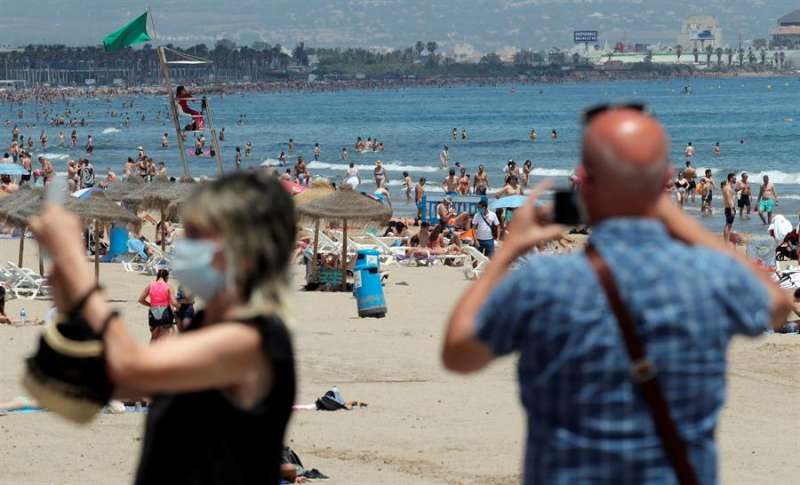 Dos personas toman fotos de la playa de la Malvarrosa, en ValÃ¨ncia, en una imagen reciente. EFE/Kai FÃ¶rsterling
