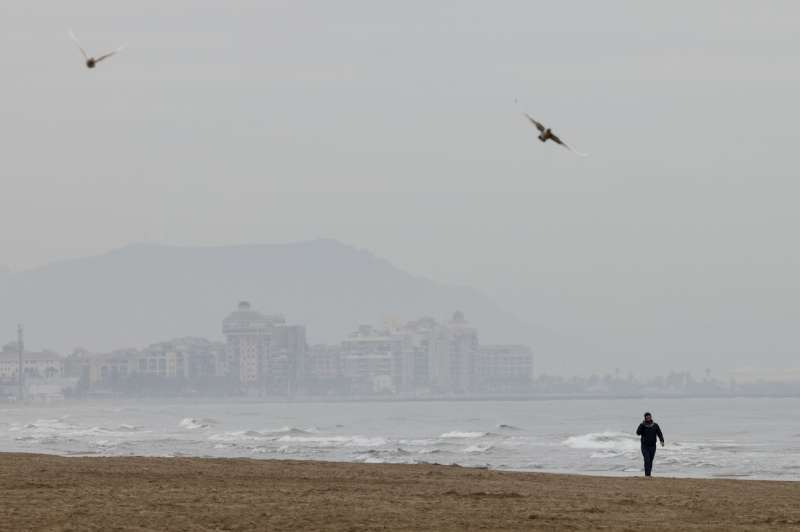 Una persona pasea por la playa, en València, en un día de nubes y viento. EFE/Ana Escobar/Archivo
