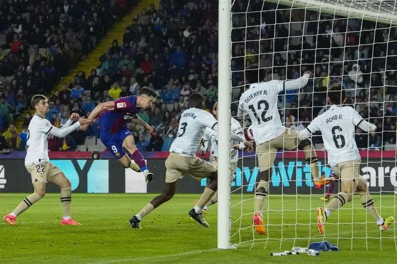 El delantero polaco del FC Barcelona Robert Lewandowski (2i) remata de cabeza para marcar su segundo gol durante el partido de la jornada 33 de Liga en Primera División que FC Barcelona y Valencia CF disputaron en el Estadio Olímpico Lluis Companys. EFE/Enric Fontcuberta.