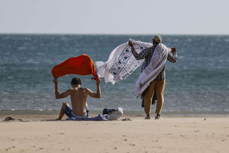 Dos personas observan como el fuerte viento agita sus toallas en la playa de la Malvarrosa de Valncia. EFEAna Escobar