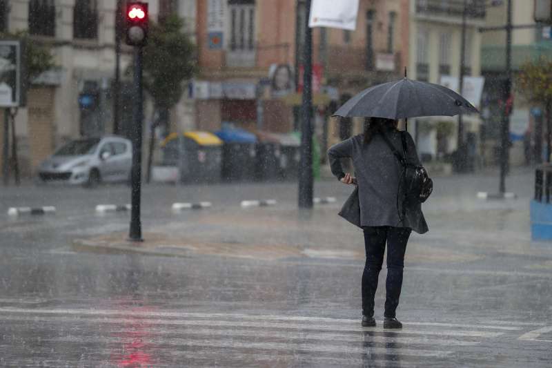 Una persona se protege de la lluvia. EFEManuel BruqueArchivo
