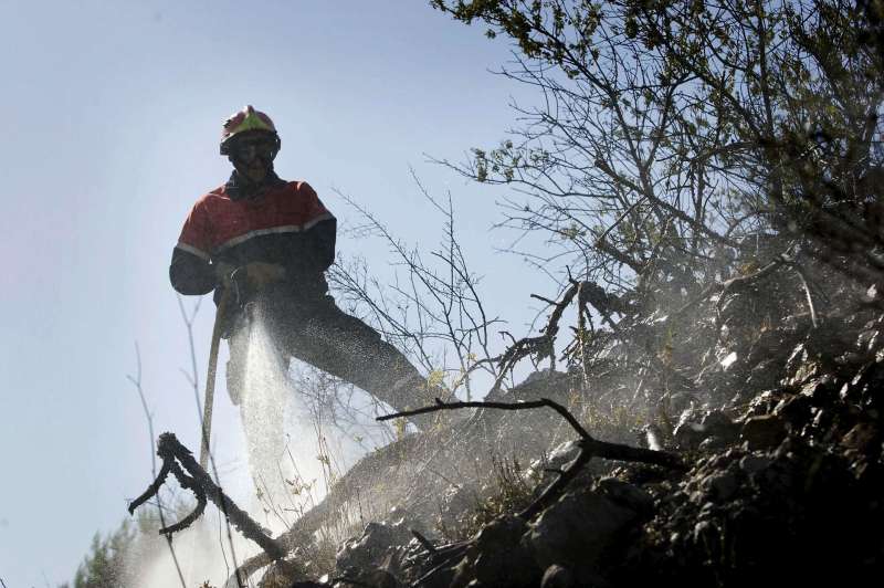 Un bombero refresca una zona arrasada por un incendio forestal. EFE/Rubén Francés/Archivo