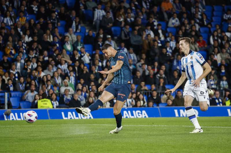 El delantero ucraniano del Valencia Roman Yaremchuk (i) efecta un lanzamiento durante el partido de LaLiga entre la Real Sociedad y el Valencia, este jueves en el Reale Arena. EFE/ Javier Etxezarreta
