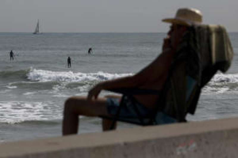 Un hombre se refresca en la playa de la Malvarrosa al atardecer.   EFE