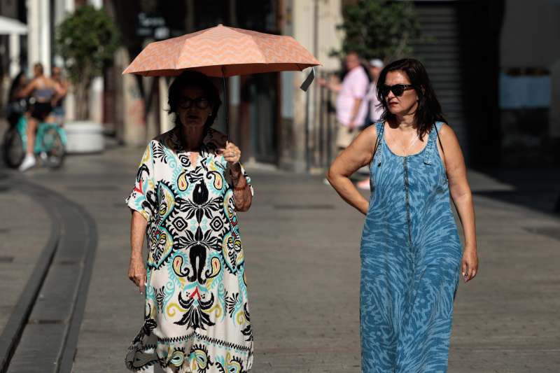 Una mujer se cubre con una sombrilla del intenso sol de hoy viernes por las calles del centro histórico de Valencia. La previsión del tiempo para este fin de semana habla de temperaturas que continuarán siendo altas. EFE