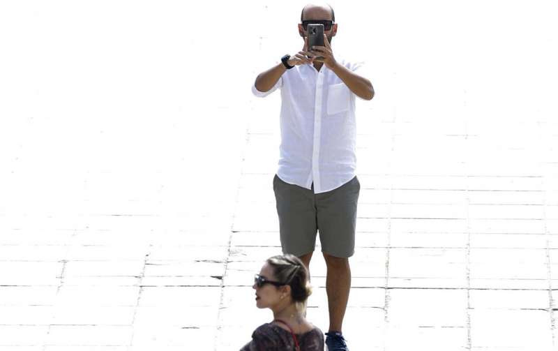 Una pareja se hace una foto a pleno sol en el centro de la ciudad de València. EFE/Biel Aliño
