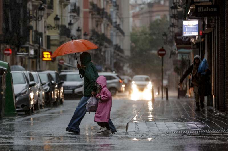 Dos personas crucen la calle lloviendo. EPDA
