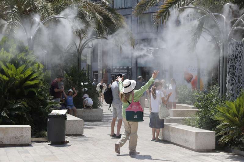 Varios turistas tratan de mitigar el calor bajo una nube de agua vaporizada en la plaza de la Reina de Valncia. EFEManuel BruqueArchivo
