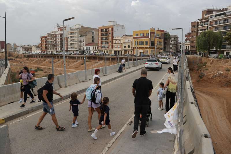 Varias familias cruzan el barranco del Poyo camino al colegio durante este lunes en el que comienza el curso escolar 2025-2026 en la Comunitat Valenciana. EFEManuel Bruque
