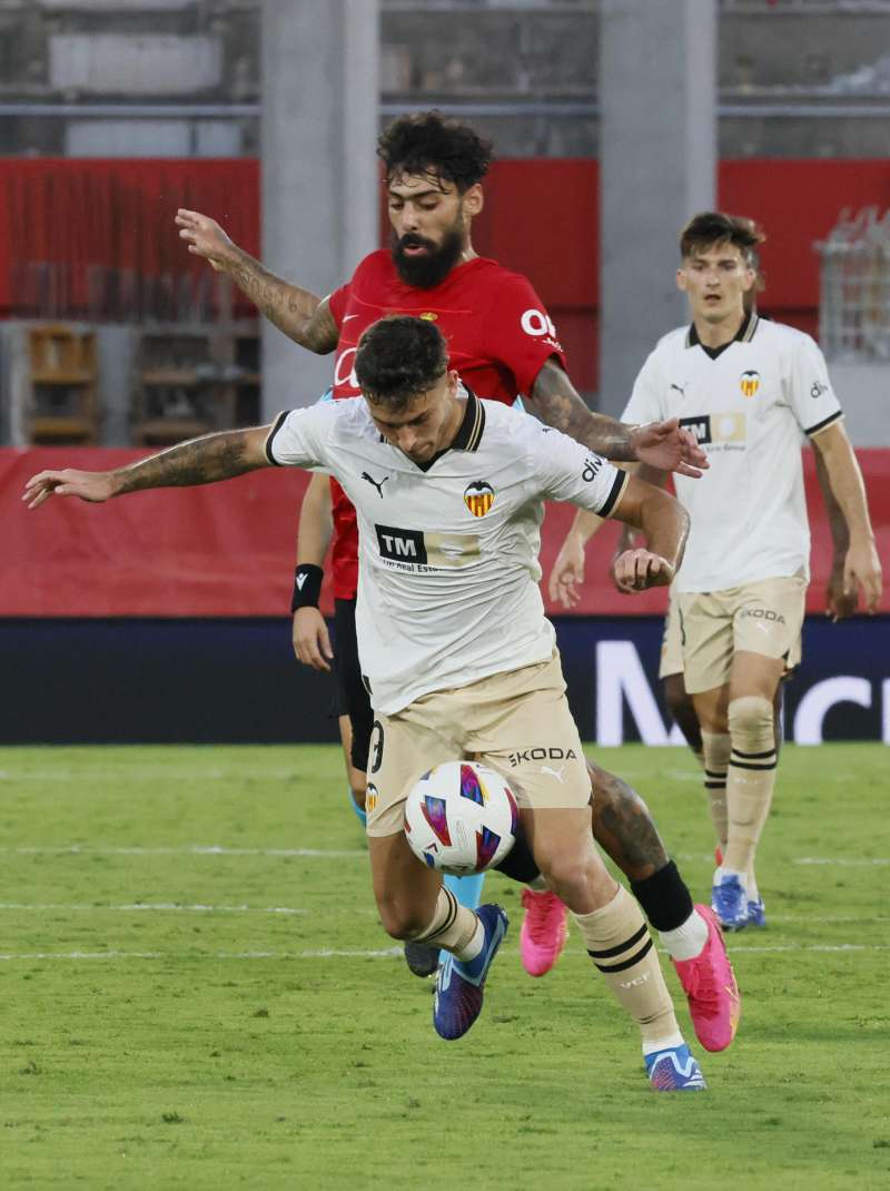 El delantero del Valencia, Hugo Duro, protege el balón ante el jugador del Mallorca, Samu Costa, en el encuentro de la jornada nueve de primera división. EFE/Archivo