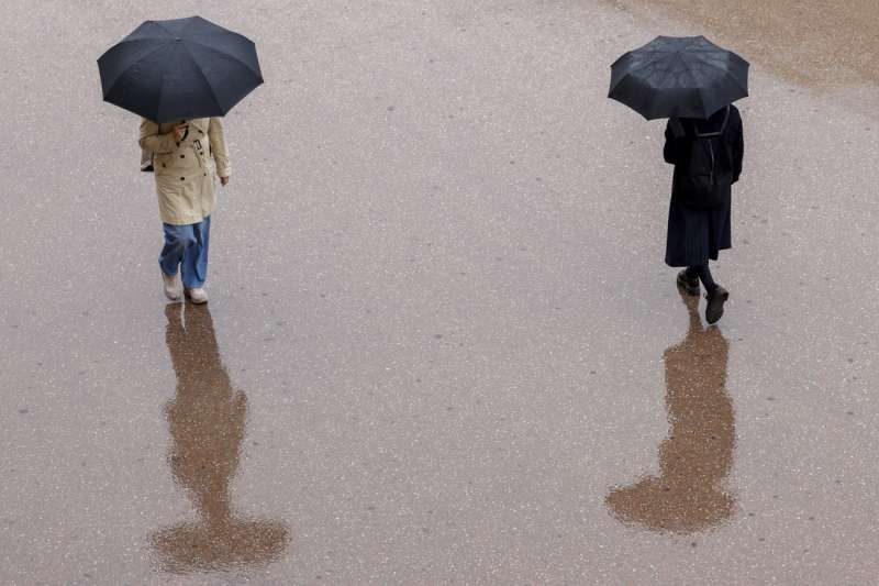 Dos personas se protegan este lunes de la lluvia con un paraguas en Valncia. EFEAna Escobar
