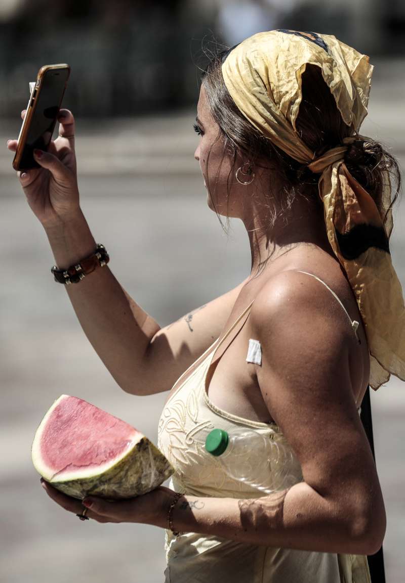 GRAFCVA7244. VALENCIA, 18/07/2022.- Una jóven turista lleva una porción de sandía y una botella de agua para combatir el calor en Valencia. EFE/Ana Escobar/Archivo