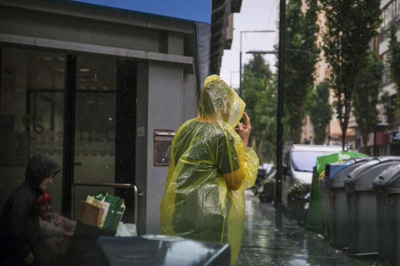 Una persona se protege de la intensa lluvia este viernes en Alicante. EFE  Pablo Miranzo