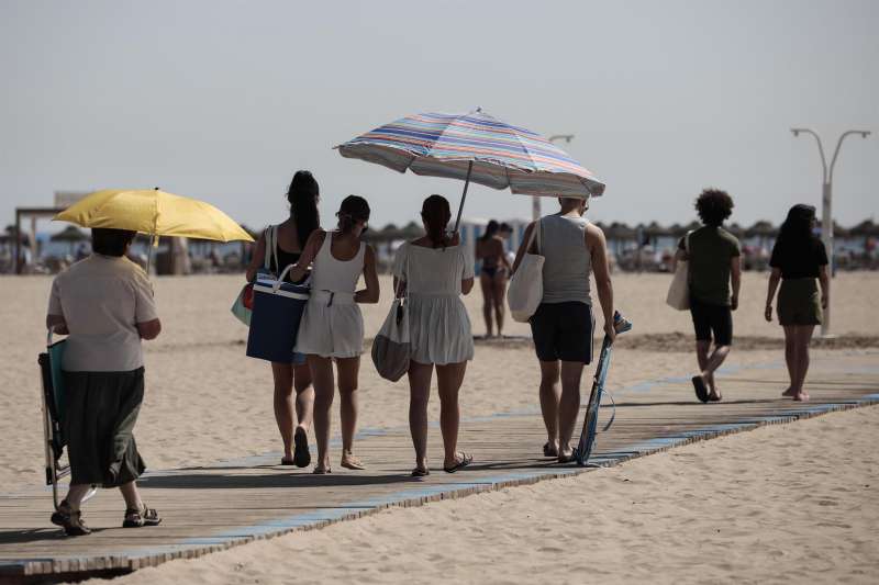  Varias personas se protegen del sol con sombrillas en la playa de las Arenas de Valencia.EFE/Ana Escobar