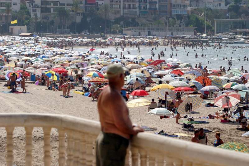 Un hombre observa la gran cantidad de turistas que hay en la Playa de Poniente de Benidorm. /EFE
