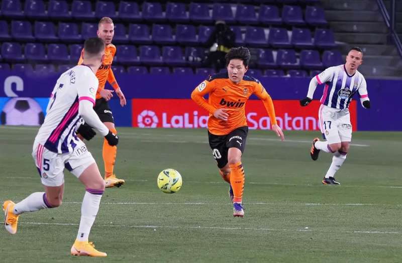 El centrocampista del Valencia Lee Kang-In (c) juega un balón ante Javier Sánchez, del Real Valladolid. EFE/R. García