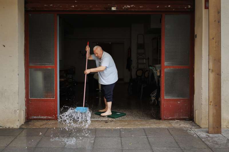 Una persona achica agua de un local comercial tras las fuertes lluvias de anoche. EFE/Biel Aliño