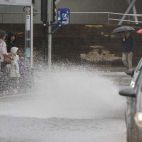 Varias personas se resguardan de la lluvia en una parada de autobús en Alicante. EFE/Morell

