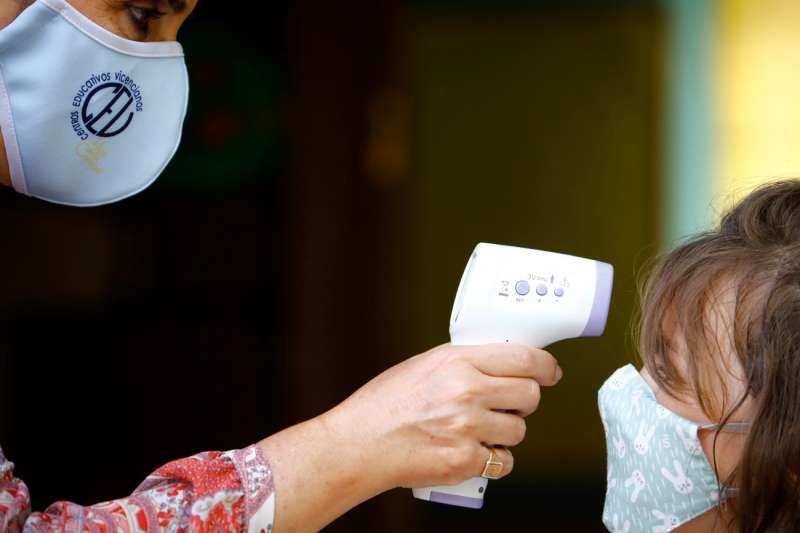 Una profesora toma la temperatura a una niña antes de entrar al colegio. EFE/Archivo
