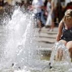 Un mujer mojando los pies en una fuente por el elevado calor. / EPDA