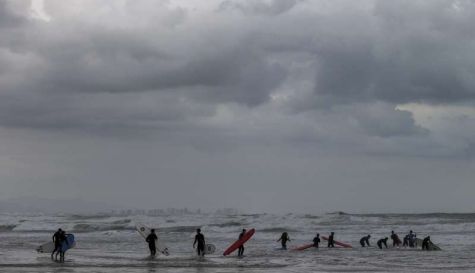 Un grupo de surfistas en la playa de la Malvarrosa en un día nublado. / EFE-Manuel Bruque
