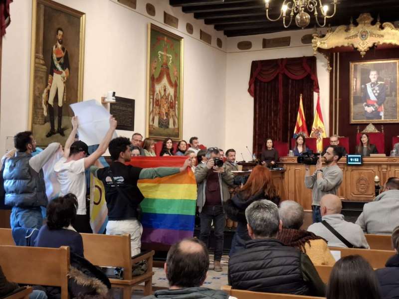 Tres jóvenes despliegan banderas del colectivo LGTBIQ+ durante el pleno del Ayuntamiento de Elche de este martes. EFE/Majo Sala
