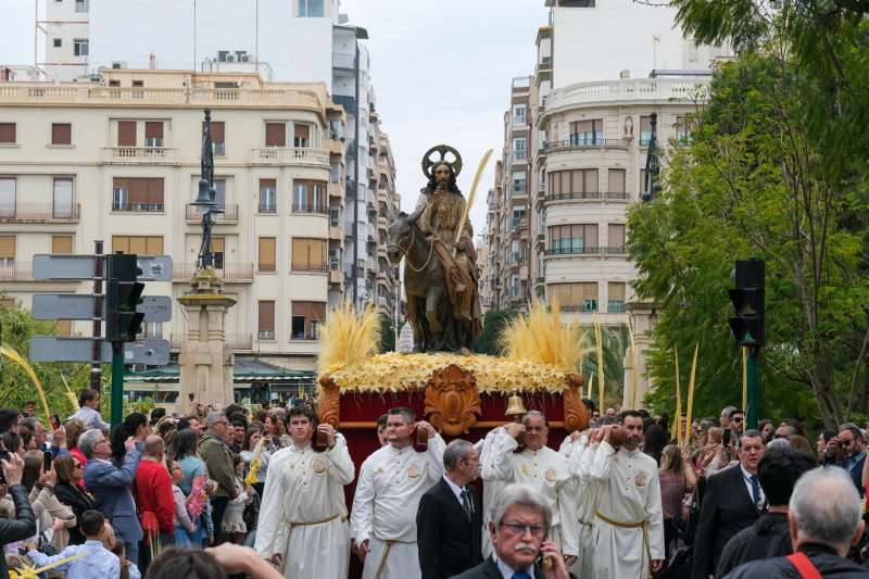 La imagen de Jesús Triunfante, conocida como "La Borriquita", durante la procesión del Domingo de Ramos que recorre las calles de Elche, este domingo, con miles de personas portando palmas blancas artesanales, símbolo distintivo de la ciudad. EFE/ Pablo Miranzo

