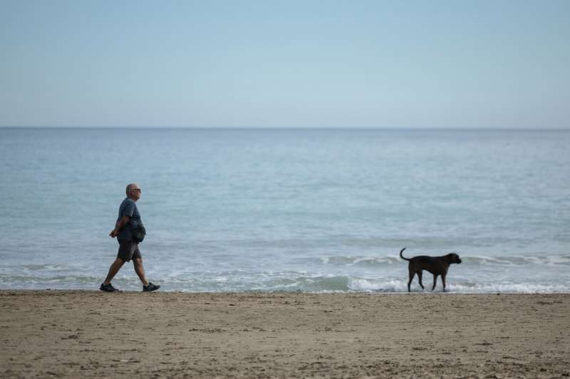 Un hombre pasea a su perro por la playa en Canet de Berenguer.