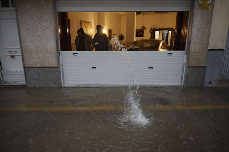 Unas personas achican agua de un garaje en la localidad de l"Alcúdia  este domingo. -EFE/ Kai Forsterling