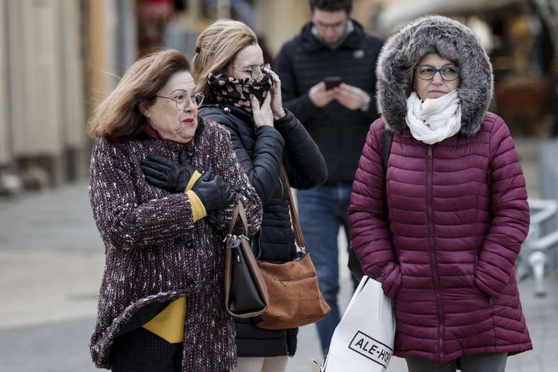Tres mujeres protegidas contra el viento y el frio pasean este lunes por el centro de Valencia. EFE/Manuel Bruque
