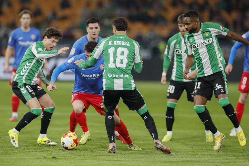 El delantero del Elche, Josan (2i), intenta llevarse el baló ante los jugadores del Betis, el colombiano Nelson Deossa y Rodrigo Riquelme, durante el encuentro correspondiente a los octavos de final de la Copa del Rey que disputan Betis y Elche en el estadio de La Cartuja, en Sevilla. EFE / José Manuel Vidal.