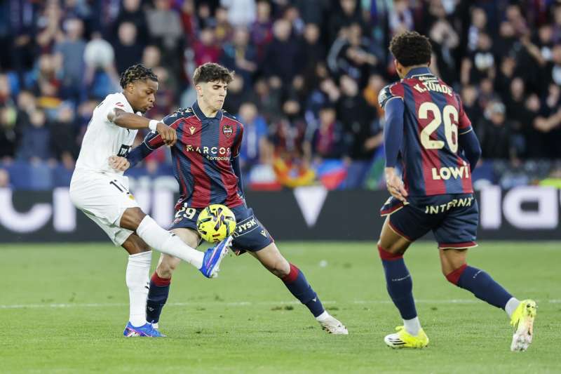 Nacho Pérez (c), del Levante, y Ramazani (i), del Valencia, durante el derbi de este domingo en el estadio Ciutat de Valencia. EFE/Ana Escobar
