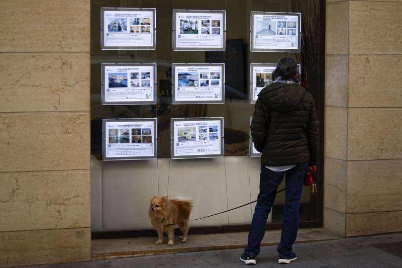 Una persona pasa ante los anuncios de venta y alquiler de vivienda en una inmobiliaria de Valencia. EFE/Biel Aliño
