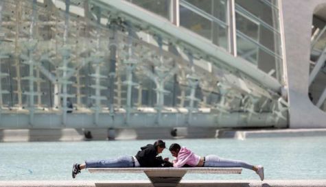 Dos personas descansan al sol sobre un banco de Ciudad de las Artes y de las Ciencias / EFE - Biel Aliño - Archivo