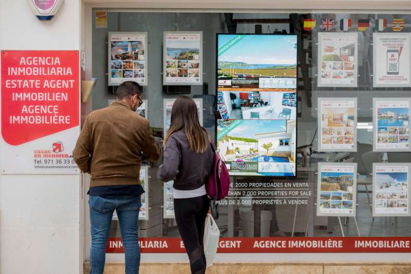 Una pareja se detiene a observar las propiedades en venta anunciadas en el escaparate de una agencia inmobiliaria. EFE/ David Arquimbau Sintes
