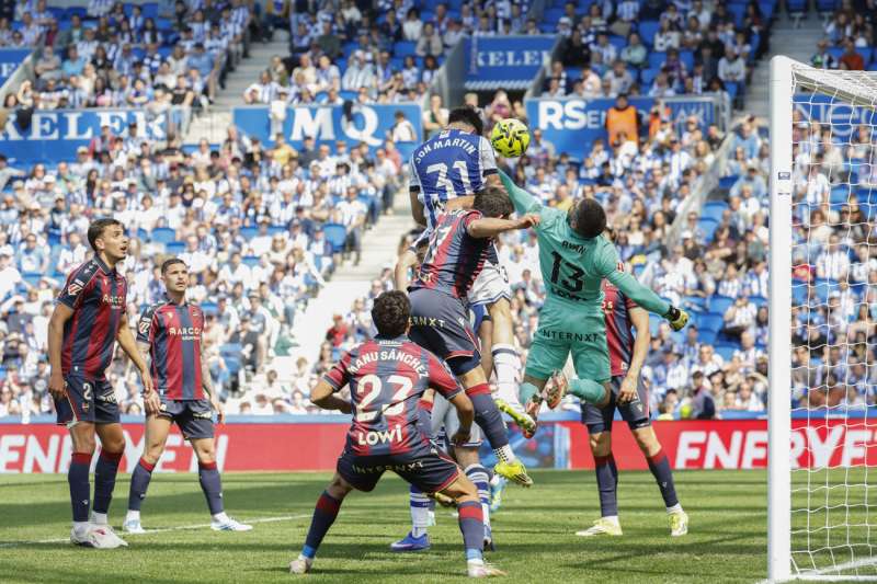 El futbolista de la Real Sociedad Jon Martín (c, arriba) bate la portería de Matthew Ryan (d), para marcar el 1-0 al Levante UD durante el partido de LaLiga EA Sports disputado este sábado en el Estadio de Anoeta de San Sebastián. EFE/Javier Etxezarreta
