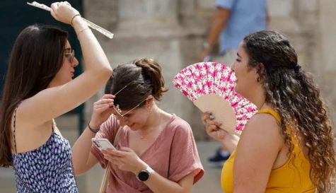 Tres personas se protegen del calor con abanicos mientras pasea por el centro de Valencia. / EFE-Kai Försterling