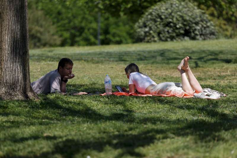 Dos personas aprovechan el buen tiempo para descansar en el antiguo cauce del Turia durante este lunes. EFE/Ana Escobar